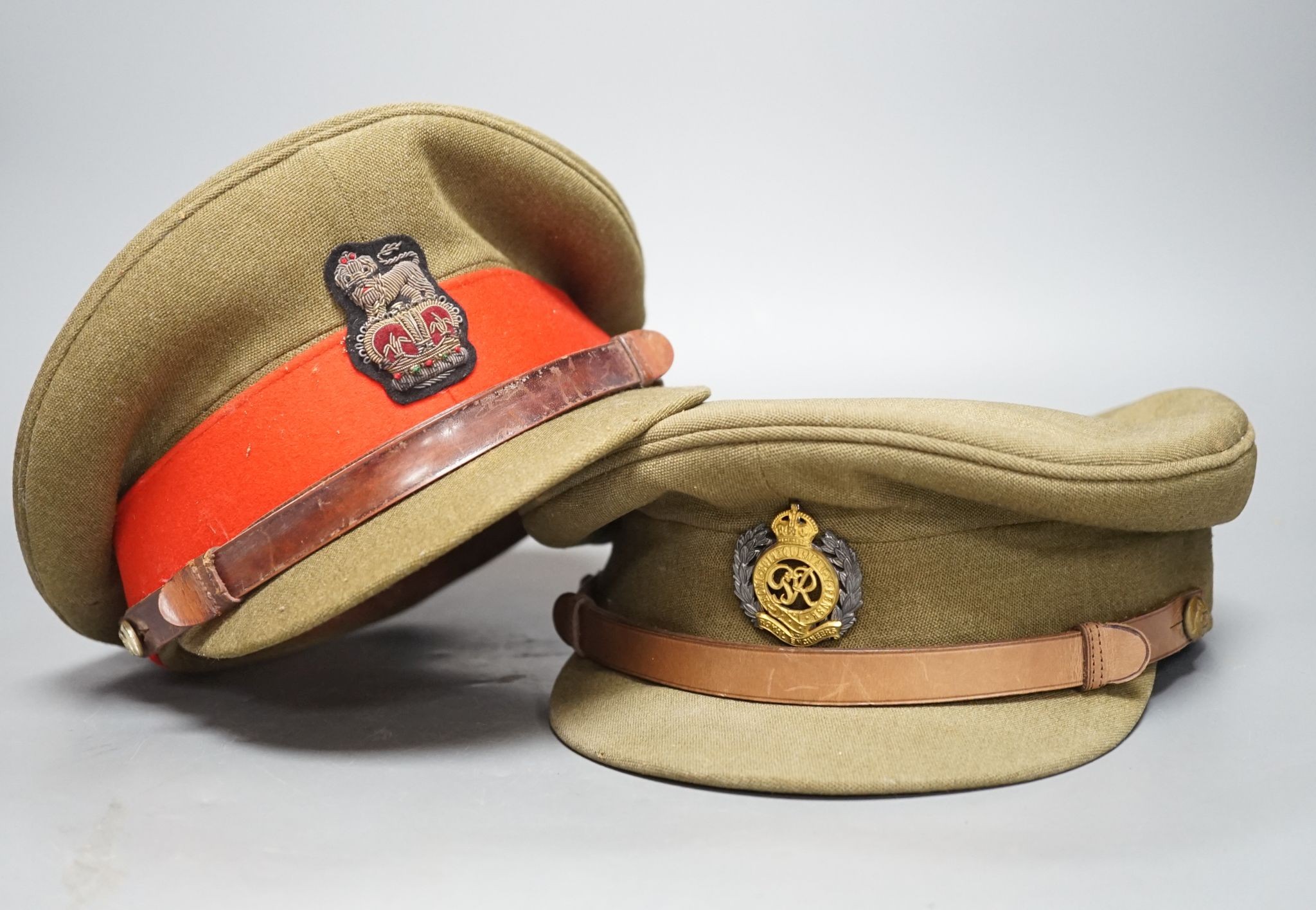 Two army officers' caps in brown leather hat box.